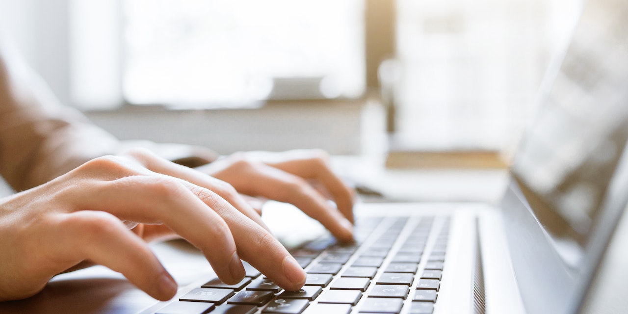 Hands typing on a notebook