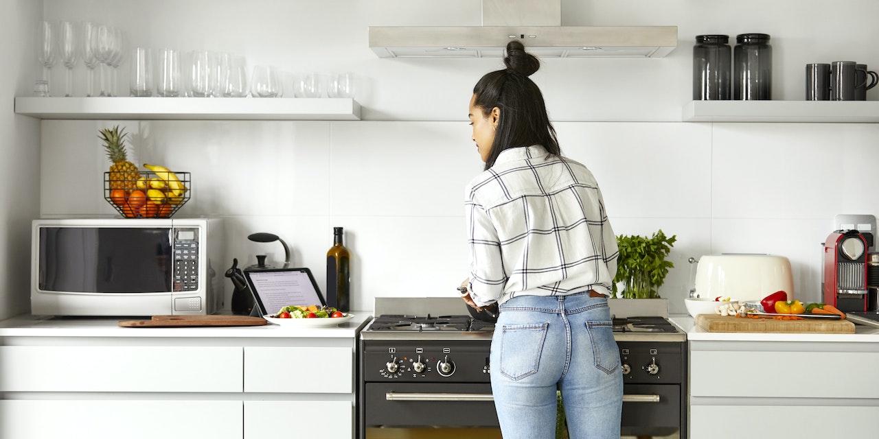 Woman cooking and checking the recipe in her tablet