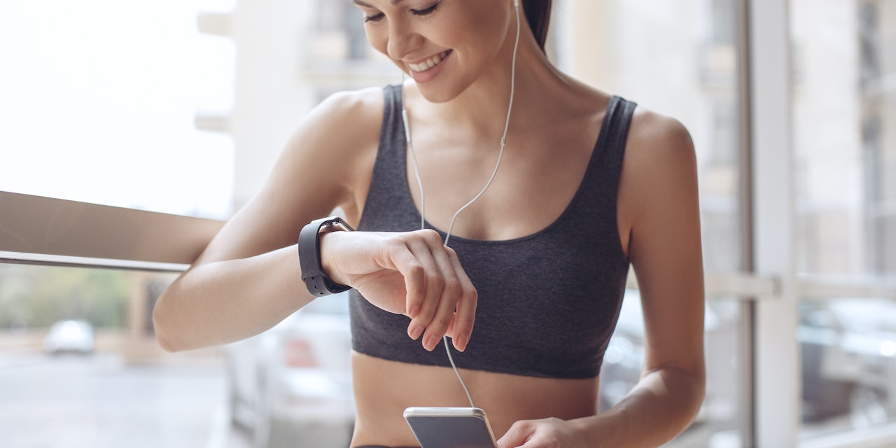 Woman training and monitoring her progress on her phone and smartwatch