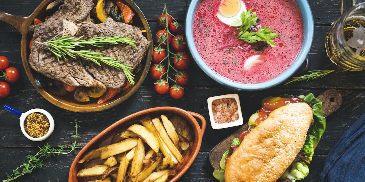 Meat, potato, soup and sandwich on a wooden table