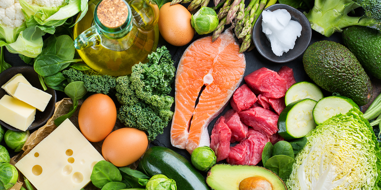 Assortment of ketogenic ingredients, such as green vegetables, meat, salmon, cheese and eggs.